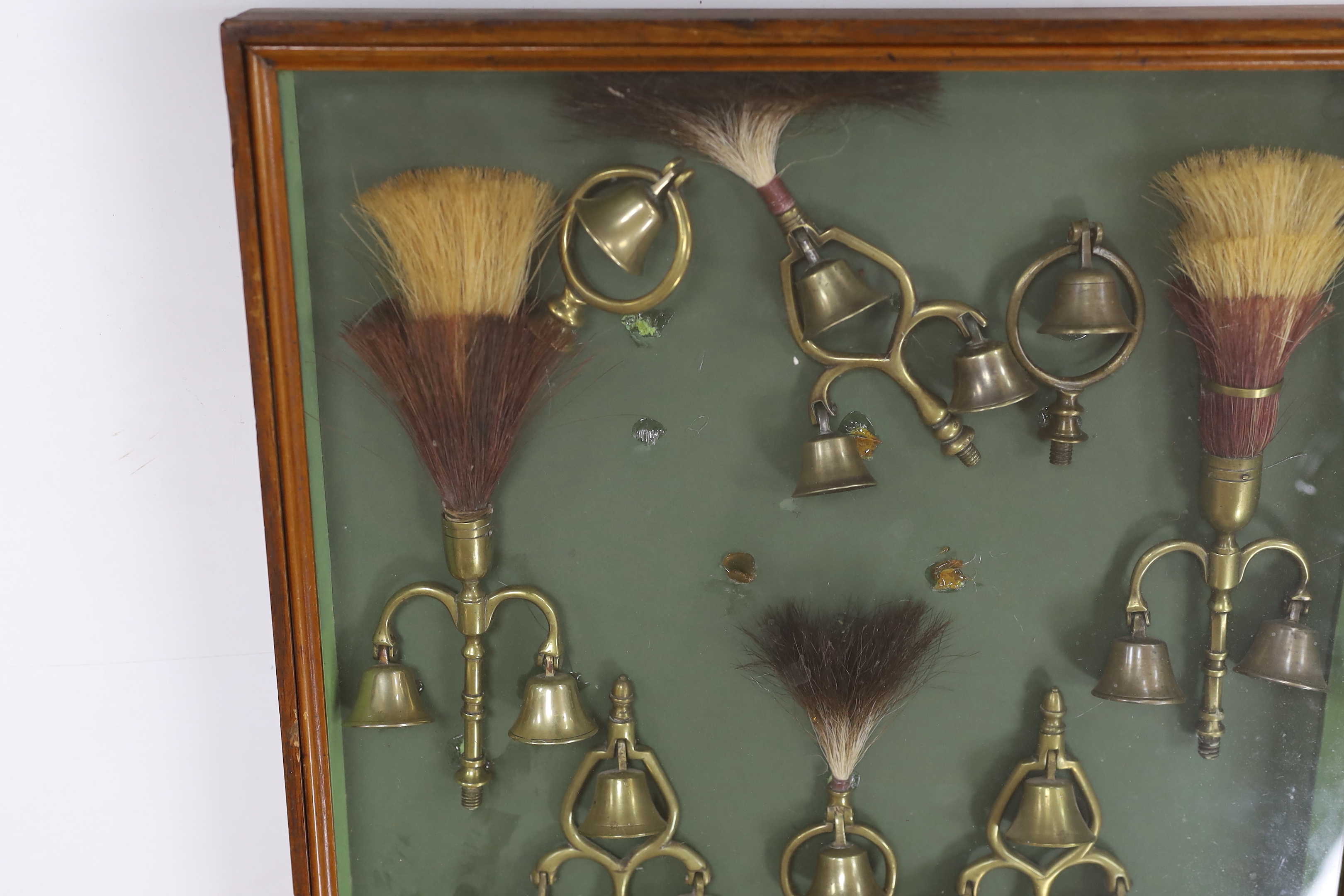 A collection of Victorian horse brass bell terrets, housed in a display case, 46cm high